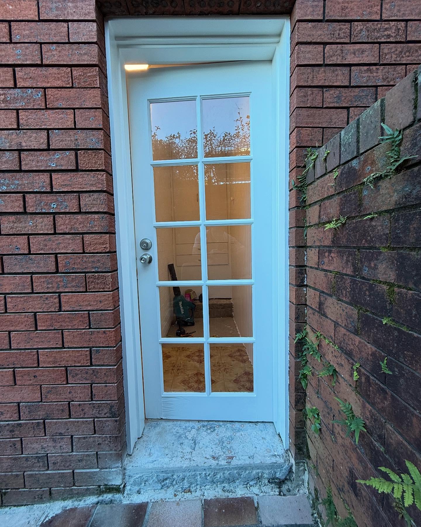 Freshly painted white door framed by red brick in the Cessnock area by Hughesys Painting