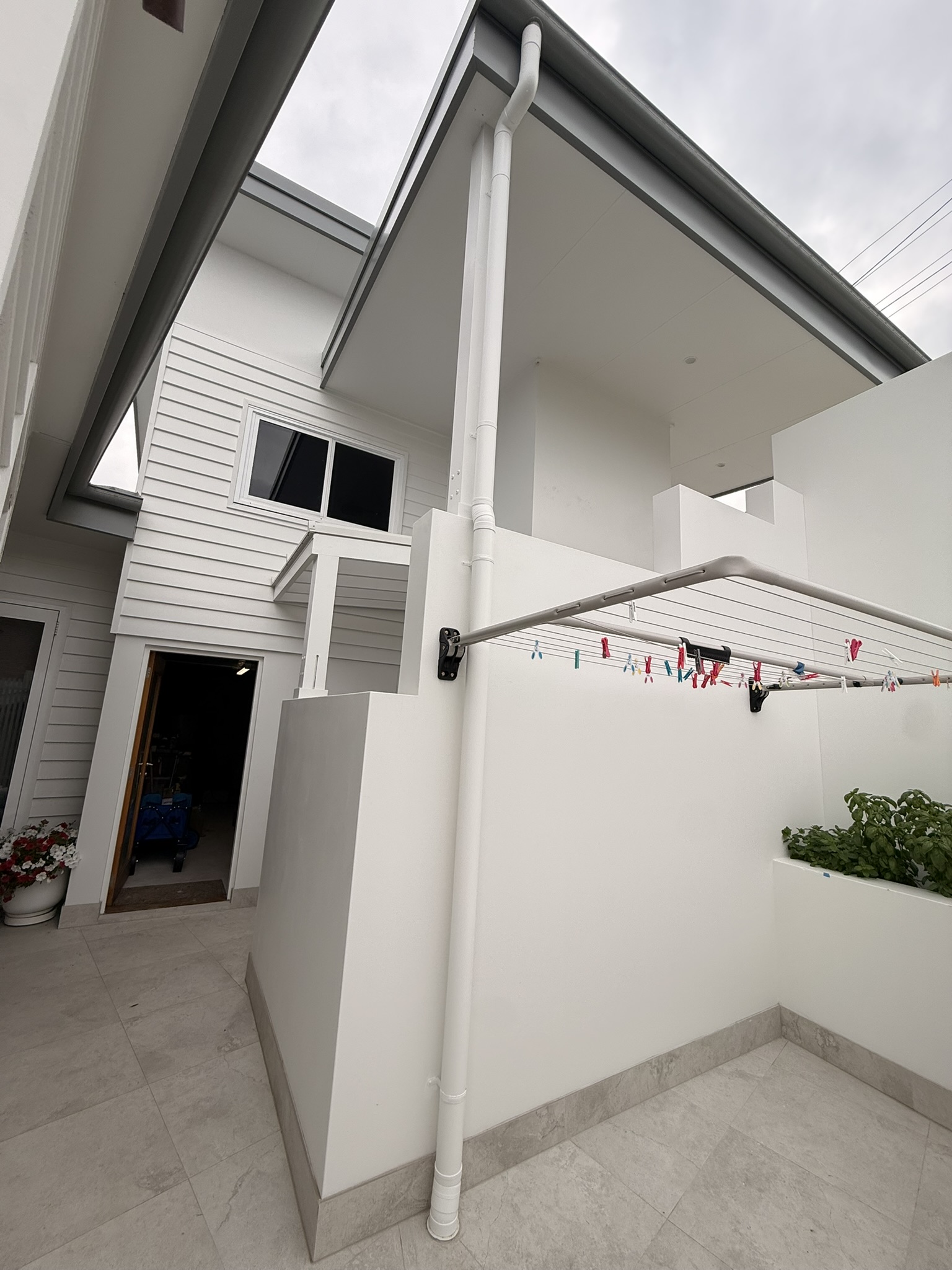 Dark gutter and fascia with a white downpipe on a painted home exterior