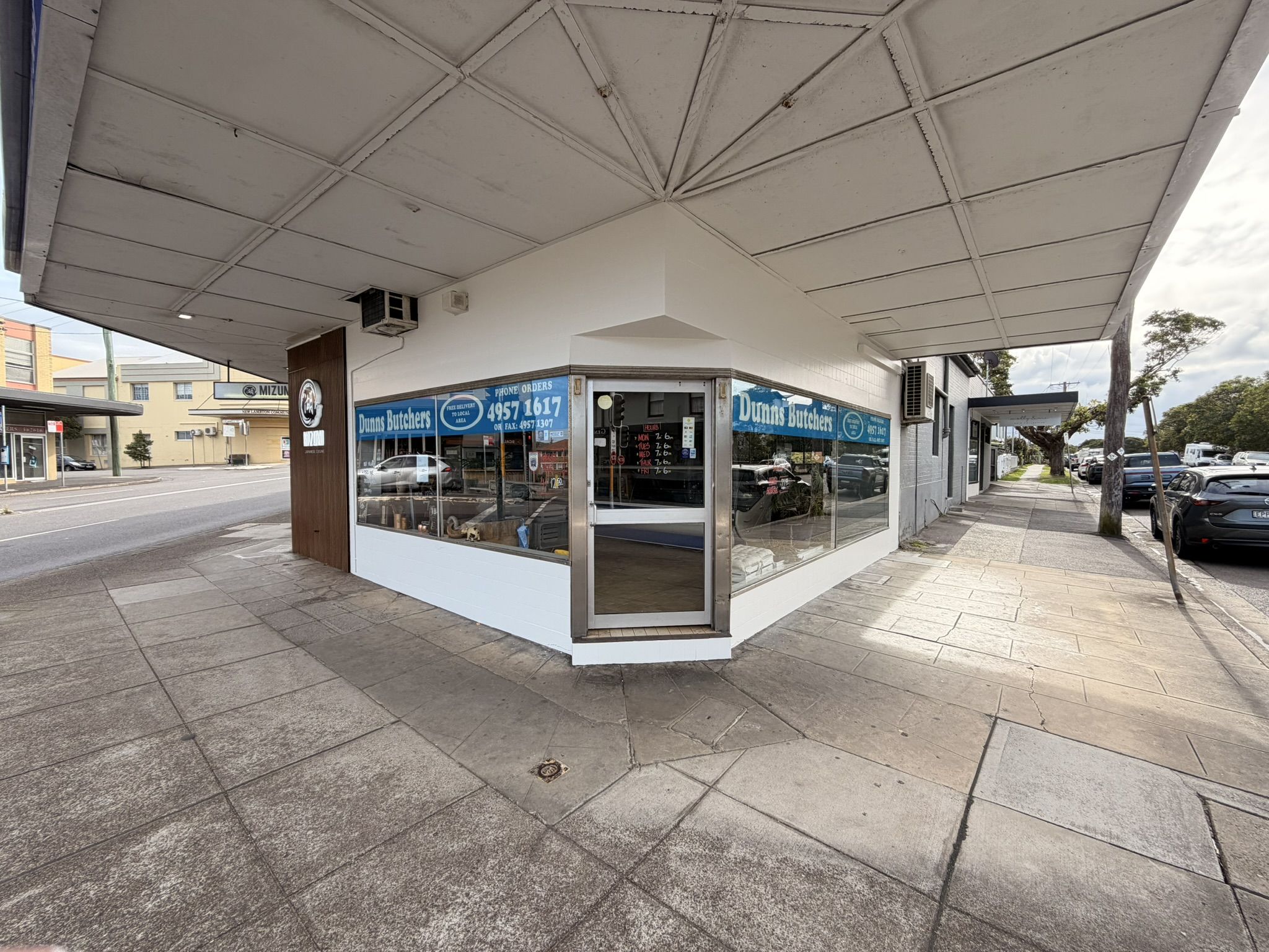 A New Lambton corner butcher shop after its repaint, with white render, a white awning ceiling and clean window surrounds