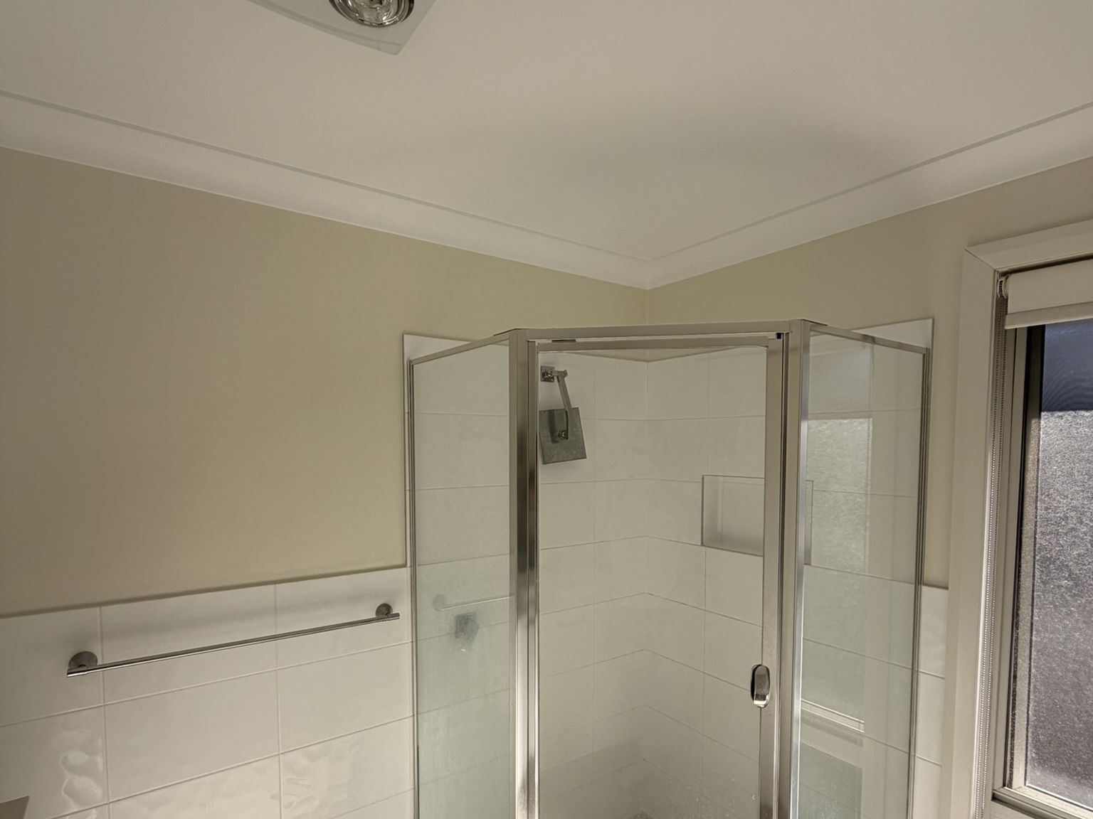 Bathroom in Cameron Park after a repaint, cream walls above white tiles and a corner shower