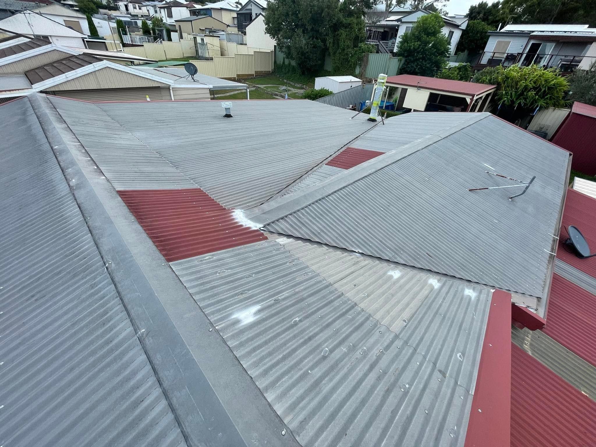 Metal roof partway through painting, the old grey finish beside the new red coat