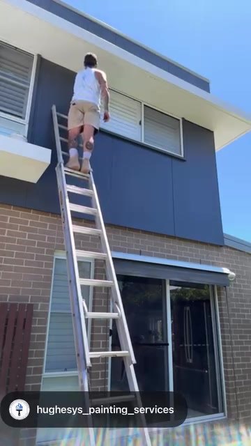 Jye Hughes painting a two-storey exterior from a ladder in Newcastle