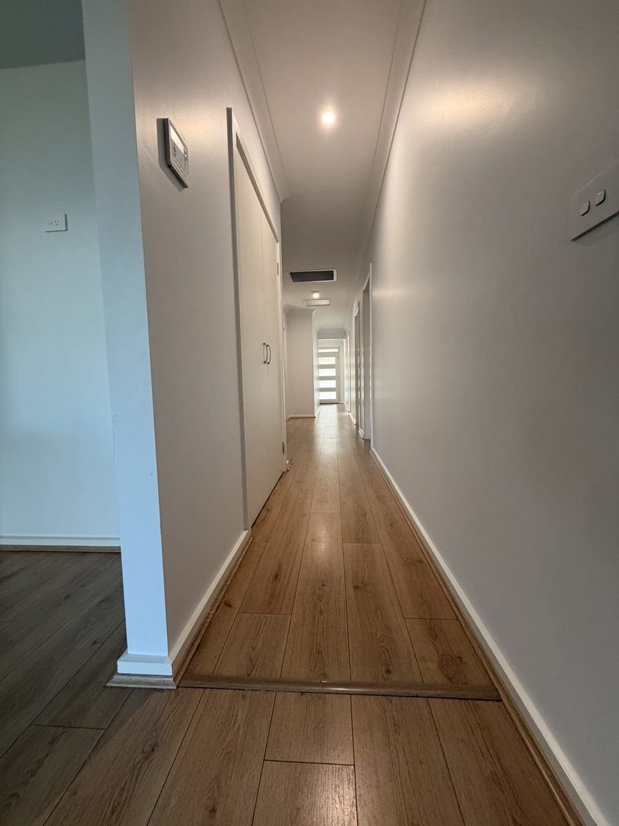 Long hallway in a Cardiff house with freshly painted white walls and a timber-look floor